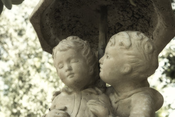 Statue of a boy whispering to a girl under an umbrella