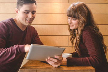 The happy couple sitting with a tablet at the restaurant table