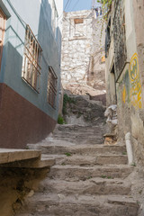 Steep and narrow stone stair passageway, with decaying stone walls with graffiti, and other architectural elements, in Guanajuato, Mexico - 192073455