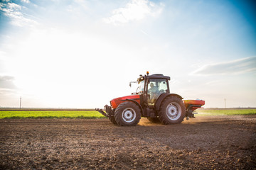 Obraz premium Farmer fertilizing arable land with nitrogen, phosphorus, potassium fertilizer