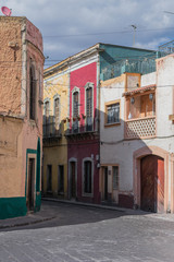 Street scene with a curve corner building painted yellow and green, a cobblestone street and other architectural details, in Guanajuato, Mexico - 192074279
