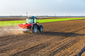 Obraz premium Farmer fertilizing arable land with nitrogen, phosphorus, potassium fertilizer