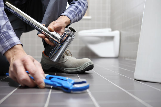 hands plumber at work in a bathroom, plumbing repair service, assemble and install concept