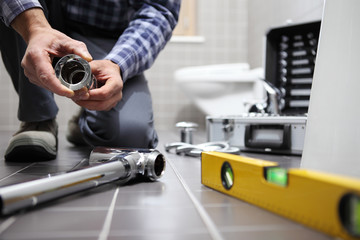 hands plumber at work in a bathroom, plumbing repair service, assemble and install concept