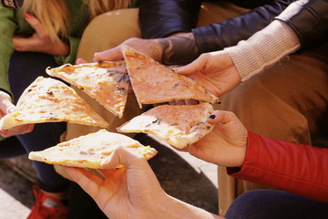 group of friends hands on pizza sharing slices of margherita pizza.