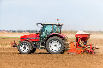 Fototapeta premium Farmer seeding, sowing crops at field. Sowing is the process of planting seeds in the ground as part of the early spring time agricultural activities.