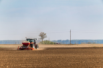 Farmer seeding, sowing crops at field. Sowing is the process of planting seeds in the ground as part of the early spring time agricultural activities.