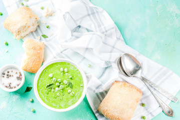 Green pea soup with fresh bread on light blue concrete table, copy space