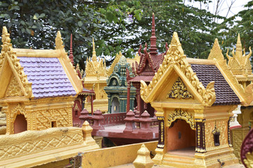 THAILAND, BANGKOK - 28 MARCH 2016 - a cluster of spirit houses sit adjacent to a roadside temple dedicated to travellers 