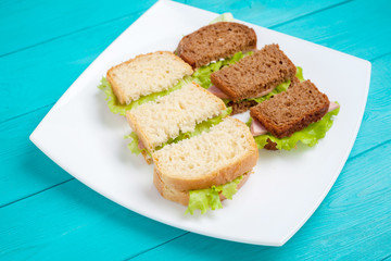 White plate with bruschetta ham and greens is on wood surfaces blue.