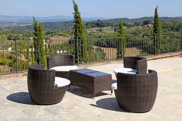 rattan table and armchairs on country terrace, Tuscany, Italy.