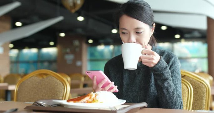 Busy woman using mobile phone in coffee shop