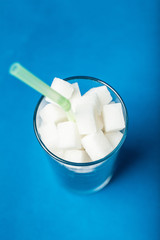 A close-up, a glass filled with sugar with a straw.