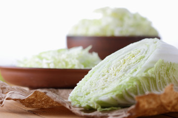 Cabbage, shredded cabbage in a clay bowl on a wooden background, home cooking, vegetarian, fresh vegetables, rustic style, Chinese cabbage on parchment paper