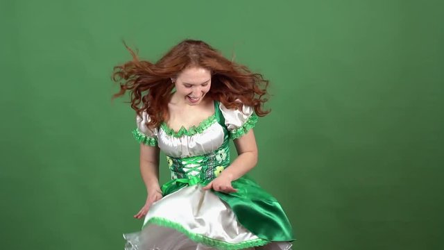 Young woman celebrating saint patrick's day on green wall wearing traditional dress windy weather