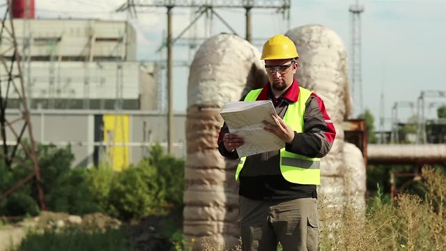 Master builder in hard hat with design drawings. Powerman with construction documentation at power plant. Worker with scheme of works on power station