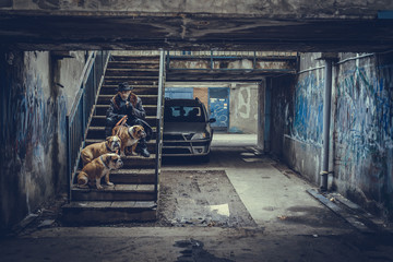 Fototapeta na wymiar Man sitting on the stairs and holding three English bulldogs