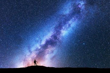 Silhouette of man with trekking poles against amazing Milky Way at night. Space background....