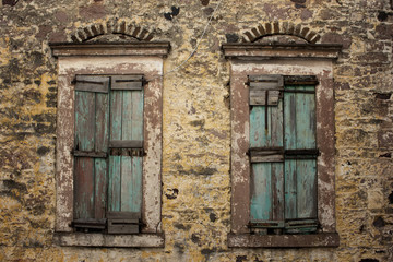 Close up view of old, rusty, closed wooden shutters and stone wa