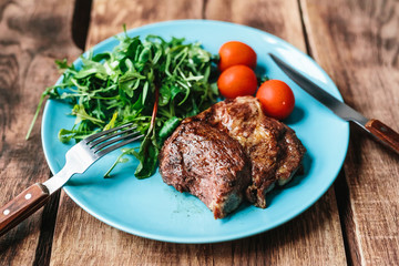 delicious steak with tomatoes and salad on a wooden background
