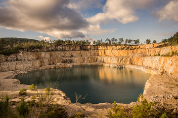 Blue lake in mining industrial crater, acid mine drainage in rock