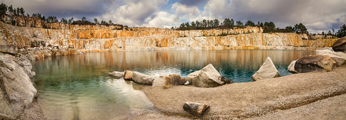 Blue lake in mining industrial crater, acid mine drainage in rock