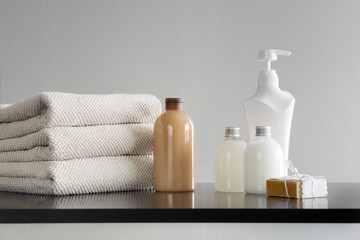Obraz na płótnie Canvas Towels with shampoo, body lotion, shower milk and handmade soap on neutral background.