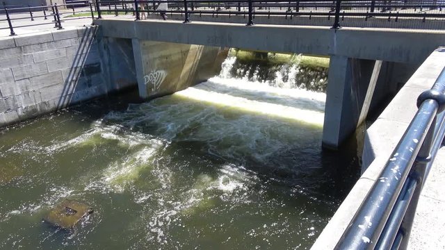 Tourists walk over man made waterfall flowing in Lachine Canal, Montreal, Canada . Wide view