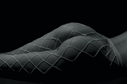 Silhouette of a body part , nude woman with fishnets on black background