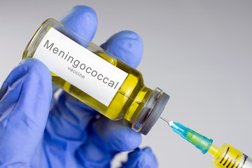 Hands in blue gloves are typing a yellow vaccine in a syringe. Meningococcal vaccination concept....