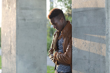Handsome young black man leaning on a wall looking down