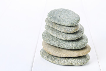 From spa stones make Balances pyramids on white wooden background.