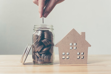 Property investment and house mortgage financial concept, Hand putting money coin stack with wooden...