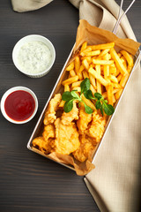 chicken nuggets with french fries and different sauces on wooden board,