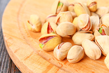 Dish full of pistachios with more pistachios on side.