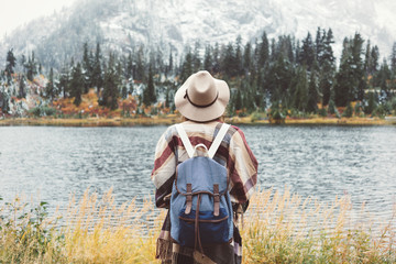 Adventure woman feeling happy among amazing mountains, enjoy the nature landsape. Forest and lake, wearing backpack, hat and poncho, boho and wanderlust style