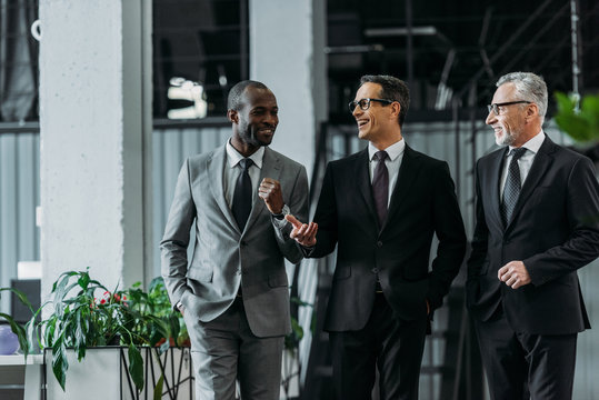 smiling multiracial businessmen having conversation while walking in office