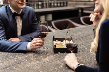cropped shot of happy adult couple drinking wine at restaurant