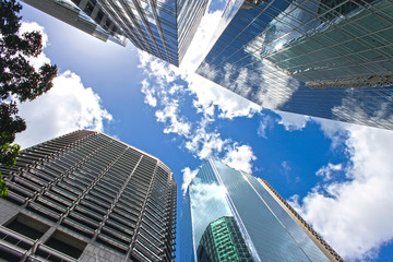 View looking up at blue cloudy sky through skyscrapers reflecting clouds and other buildings in CBD Brisbane Queensland Australia