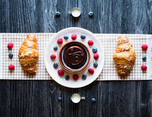 Top view of a wood table full of cakes, fruits, coffee, biscuits, spices and more