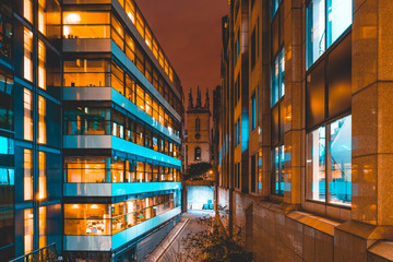 modern office buildings in the night with a small church in the middle at london