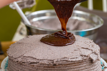 Pouring chocolate icing on a cake
