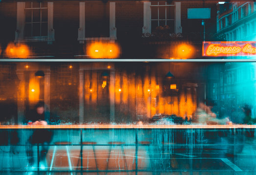 blurred glass facade of espresso bar in winter with orange lights inside and cold blue colors outside the window