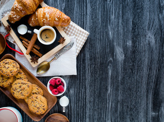 Top view of a wood table full of cakes, fruits, coffee, biscuits, spices and more