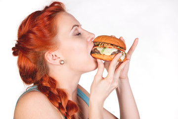young woman eating  hamburger in profile