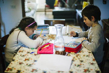 children sitting at the table at home perform homework