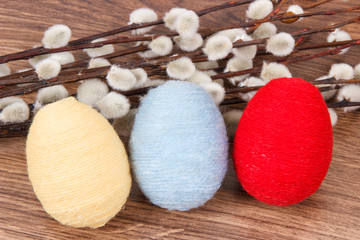 Easter catkins and eggs wrapped woolen string on rustic board, festive decoration
