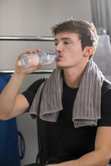 Young man drinking water from a plastic bottle after workout