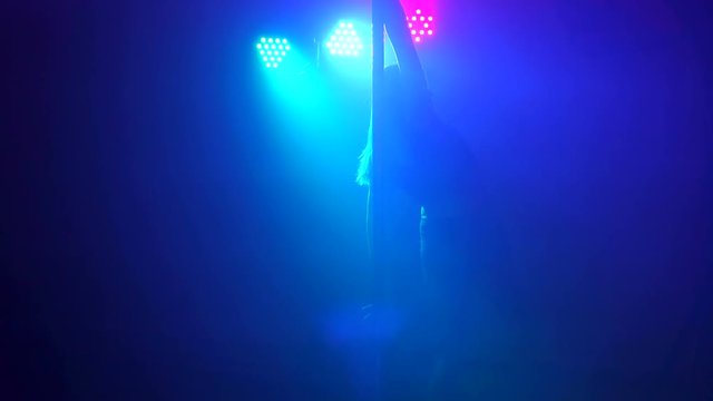 Pole dance. Beautiful girl spinning around pylon, slow motion.