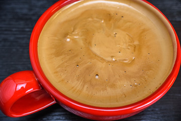 fresh aromatic coffee in a red mug on a black wooden background